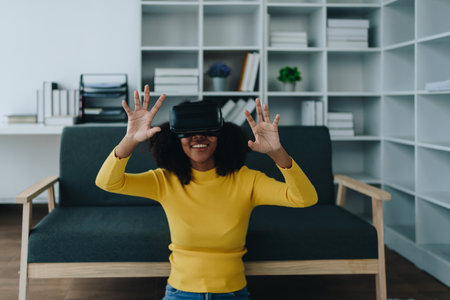 Positive African American woman teenager in futuristic VR helmet laughing and relaxing. Youthful...