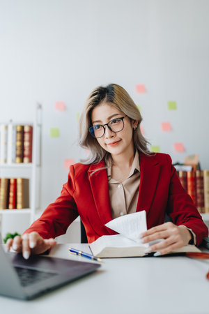 Portrait of a Asian woman lawyer studying lawsuit a for a client using computer laptop , documents...