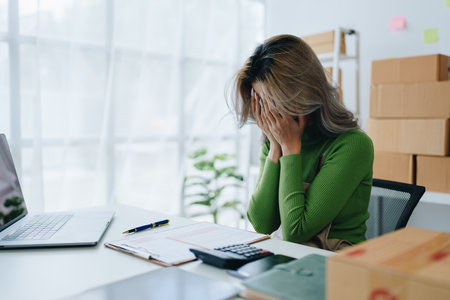 Starting small business entrepreneur of independent Asian woman showing her face worried about the sales of her business not reaching the target set. SME concepts.の写真素材