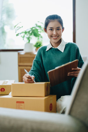 Starting small business entrepreneur of independent Asian female online seller packing products to...