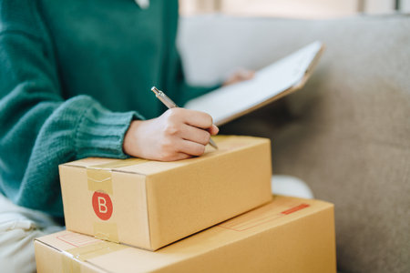 Starting small business entrepreneur of independent Asian female online seller packing products to...