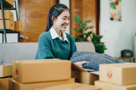 Starting small business entrepreneur of independent Asian female online seller packing products to...