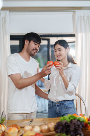 Couple cutting tomatoes for cooking or salad in home kitchen.の写真素材