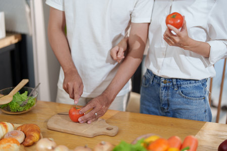 Couple cutting tomatoes for cooking or salad in home kitchen.