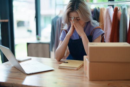 Starting small business entrepreneur of independent Asian woman showing her face worried about the sales of her business not reaching the target set. SME concepts.の写真素材