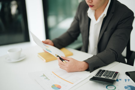 Young asian male work with financial papers at home count on calculator before paying taxes receipts online, planning budget glad to find chance for economy saving money, audit conceptsの写真素材
