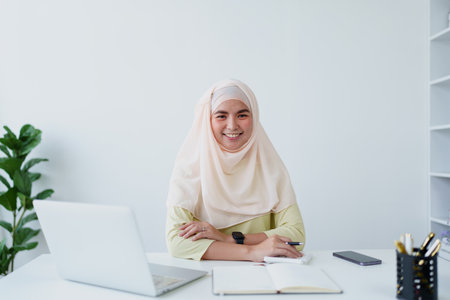 Muslim women use calculators, computers, and laptops to check their accounts at workの写真素材