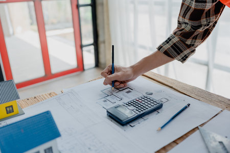 engineer brainstorming and measuring for cost estimating on blueprint and floor plan drawings about...