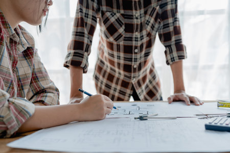 multi ethnic engineer brainstorming and measuring for cost estimating on blueprint and floor plan drawings about design architectural and engineering for houses and buildings.の写真素材