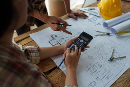 multi ethnic engineer brainstorming and measuring for cost estimating on blueprint and floor plan...