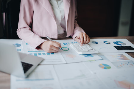 businesswoman or accountant working on calculator and laptop computer to calculate business data during using accountancy document at office.の写真素材