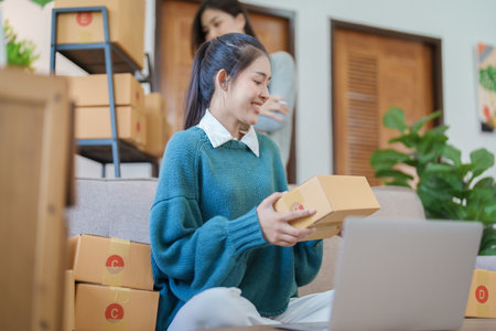 Starting small business entrepreneur of independent young Asian woman online seller is using computer and taking orders to pack products for delivery to customers. SME delivery concept.の写真素材