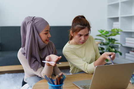 Muslim undergraduates and Asian women are studying online using computersの写真素材