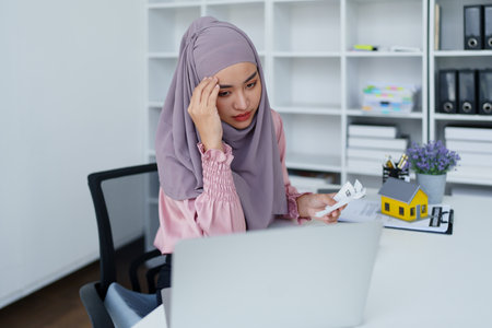 muslim woman with hijab using calculator focus on utility bills calculate check credit card receipt monthly expenseの写真素材