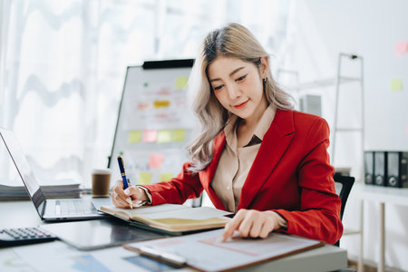 Consultant, advisor, Asian business woman working on the tablet computer work financial and marketing business plan to increase company profits, ready to use computer and marketing planning documents.の写真素材
