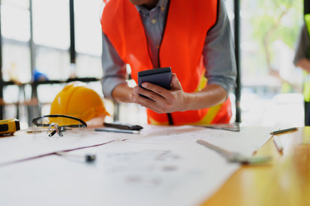 engineers discuss building on blueprint drawing using calculatorの写真素材