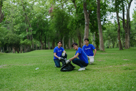 Multiethnic volunteers donate their time holding black garbage bags to collect plastic waste for recycling to reduce pollution in a public parkの写真素材