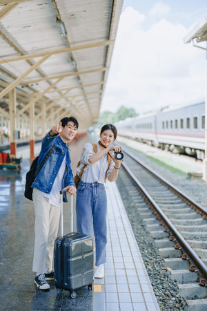 Young couple traveling using a camera to capture memories while waiting for the train at the station.travel conceptsの写真素材