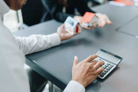 Guarantee, mortgage, contract, contract, signed, real estate agent or bank officer holding a calculator, submits a bid with a customer to buy a home before signing to make a deal.の写真素材