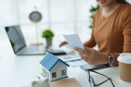 asian woman are using a calculator to calculate the loan period each monthの写真素材