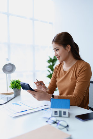 Woman Home Finance Management using calculator, computer and documents Mortgage to plan calculate.の写真素材