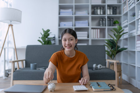 woman creates a detailed financial saving plan using a calculator to organize her expenses and ensure long-term financial stability and security.の写真素材