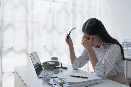 businesswoman plans a finance audit, reviewing documents while battling burnout syndrome