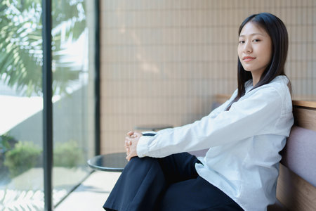 Young woman relaxing in modern indoor space with natural light and minimalist design aesthetic for peaceful ambiance.の写真素材
