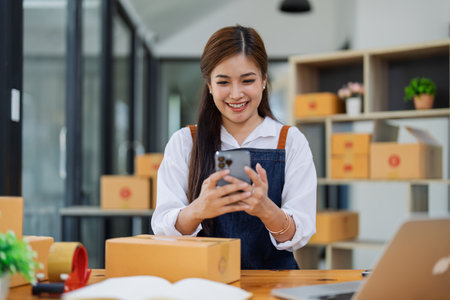 Excited young woman celebrating success while using smartphone to see data delivery products customer profit Selling products of This month.の写真素材