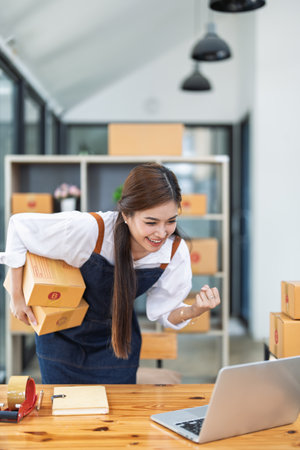 Excited young woman celebrating success while using computer laptop to see data delivery products customer profit of This monthの写真素材