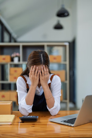 Young woman engaged in online business with stress thoughtful within data products Sales did not meet target Selling products of This month.の写真素材