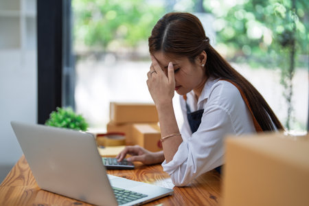 Young woman engaged in online business with stress thoughtful within data products Sales did not meet target Selling products of This month.の写真素材