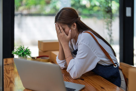 Young woman engaged in online business with stress thoughtful within data products Sales did not meet target Selling products of This month.の写真素材