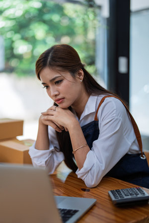 Young woman engaged in online business with stress thoughtful within data products Sales did not meet target Selling products of This month.の写真素材