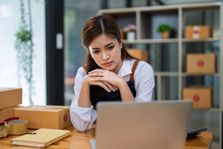 Young woman engaged in online business with stress thoughtful within data products Sales did not meet target Selling products of This month.の写真素材