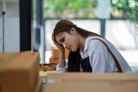 Young woman engaged in online business with stress thoughtful within data products Sales did not meet target Selling products of This month.の写真素材