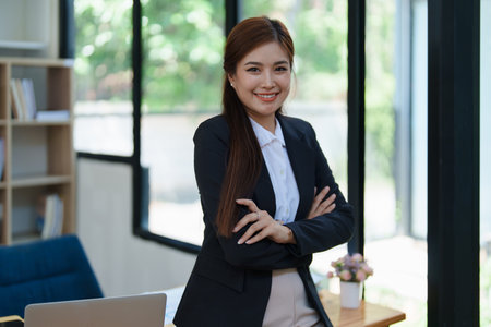 Confident business woman smiling Show successful gestures at her desk with market charts and documents in office.の写真素材