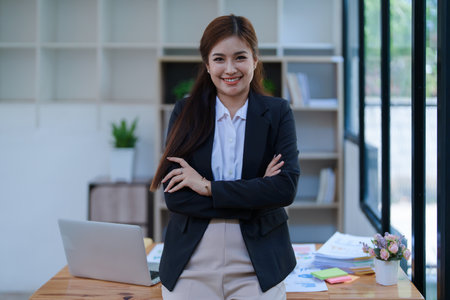 Confident business woman smiling Show successful gestures at her desk with market charts and documents in office.の写真素材