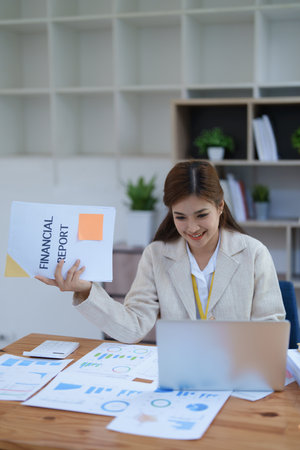 professional businesswoman planning and analyzing marketing charts and financial documents with a laptop and calculator papers on the desk.の写真素材