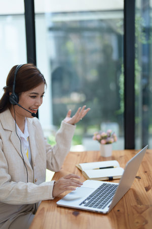 Asian businesswoman wears a headset while participation in an online video conference discussing marketing and finance strategies effectively.の写真素材