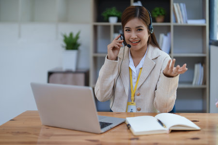 Asian businesswoman wears a headset while participation in an online video conference discussing marketing and finance strategies effectively.の写真素材