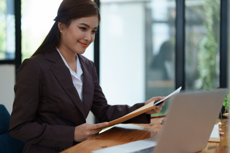 female attorney advisor at a law firm reviews legal documents at her desk equipped with a laptop notebook and scales of justice in the office.の写真素材