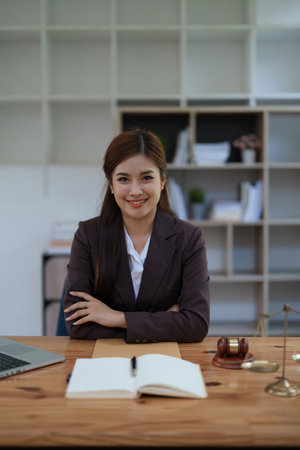 female attorney advisor at a law firm reviews legal documents at her desk equipped with a laptop notebook and scales of justice in the office.の写真素材