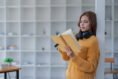 happy young woman with headphones is immersed in a book, happily learning.の写真素材