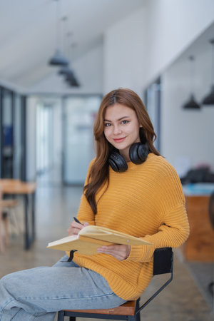 happy young woman with headphones is immersed in a book, happily learning.の写真素材