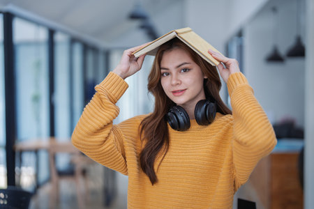 happy young woman with headphones is immersed in a book, happily learning.の写真素材