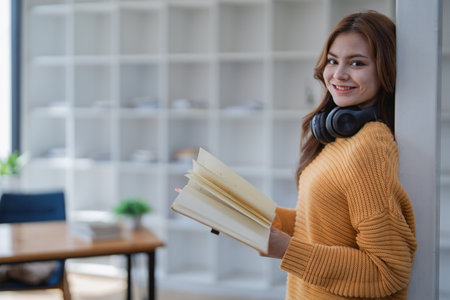 happy young woman with headphones is immersed in a book, happily learning.の写真素材