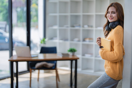 happy young woman with headphones is immersed in a book, happily learning.の写真素材