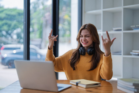 young woman happy, viewing her excellent success score in her e-learning program displayed on her laptop at her desk at home.の写真素材