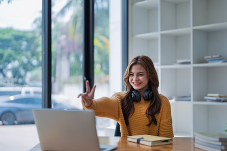 young woman happy, viewing her excellent success score in her e-learning program displayed on her laptop at her desk at home.の写真素材